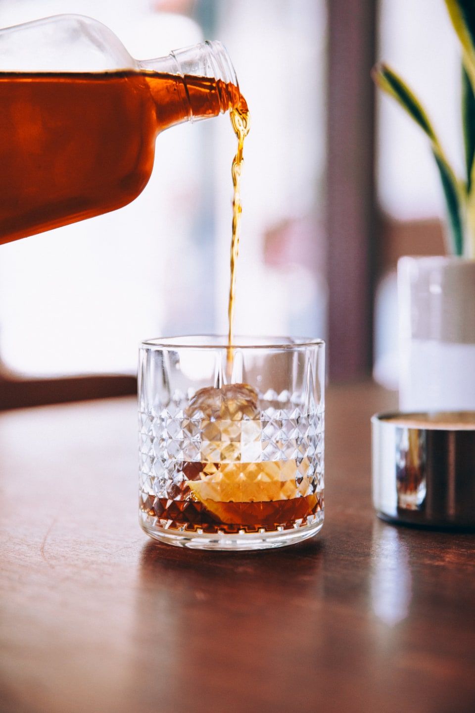 Bourbon pouring into a cut-crystal rocks glass over ice